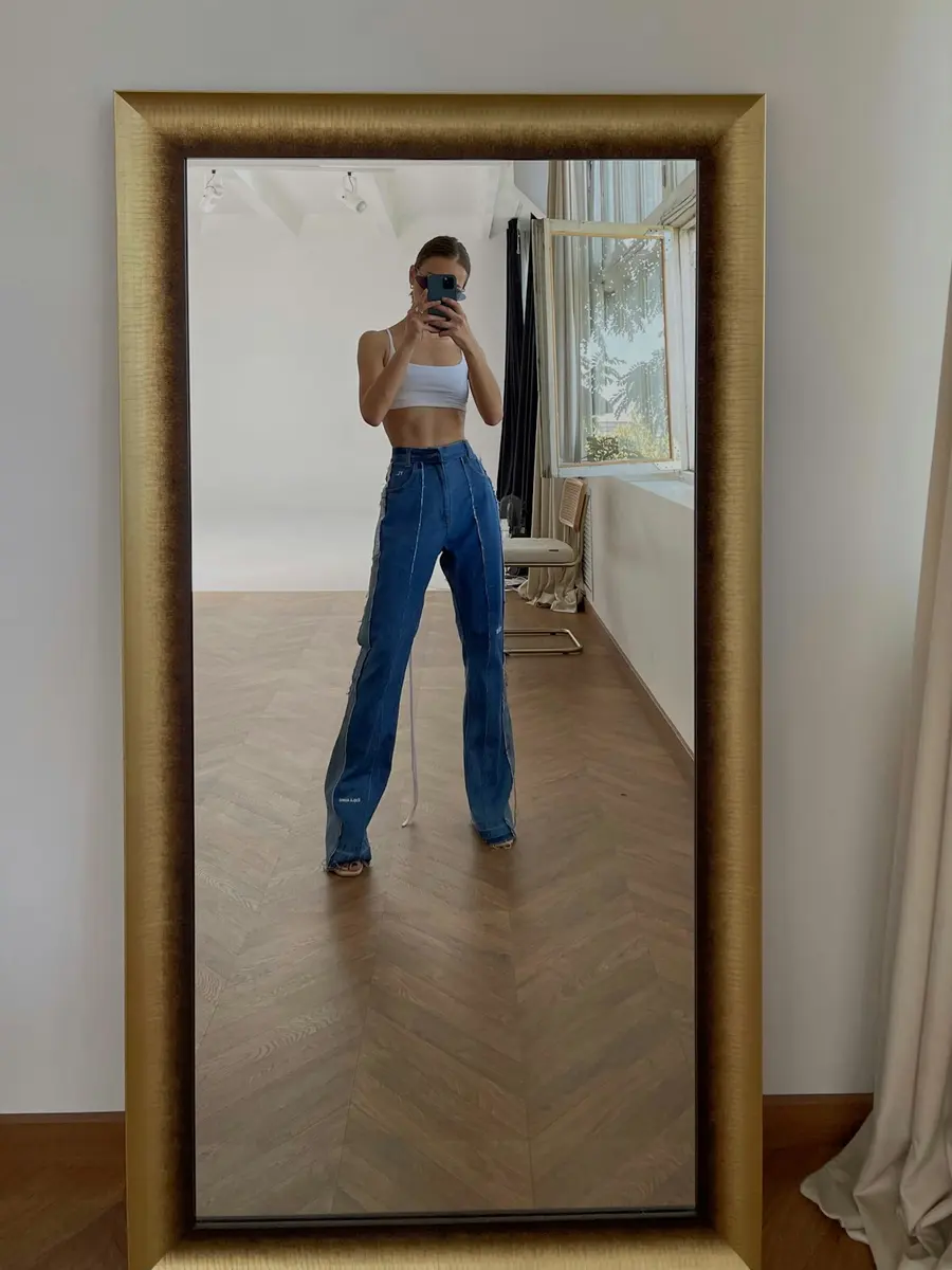 Ein fertiges Outfit im Spiegel, das Gesicht hinter dem Handy